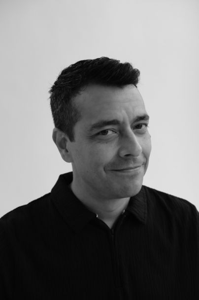Portrait of Daniel Garrido in black and white, smiling subtly.